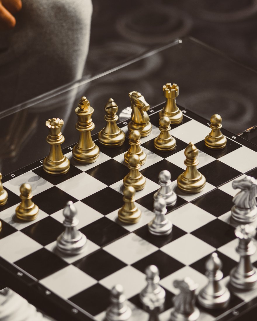 A chess board mid-game, gold pieces facing silver across the squares